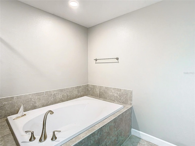 full bathroom with tile patterned flooring, a bath, and baseboards