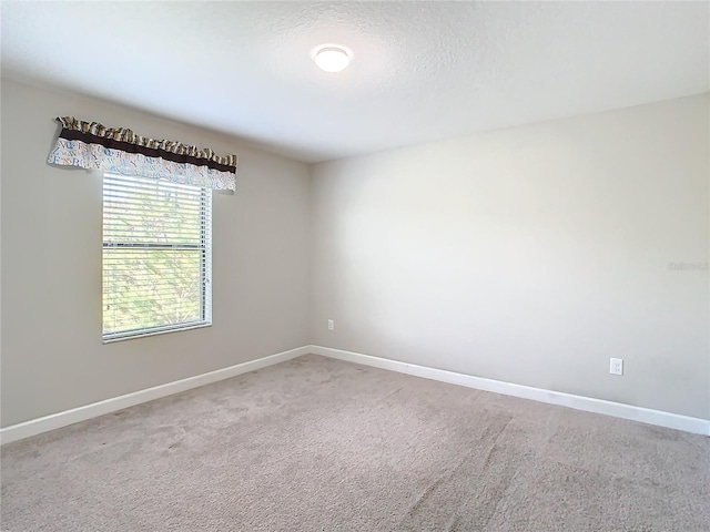 carpeted spare room featuring baseboards