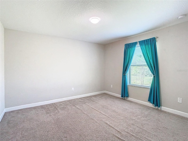 empty room featuring carpet, baseboards, and a textured ceiling