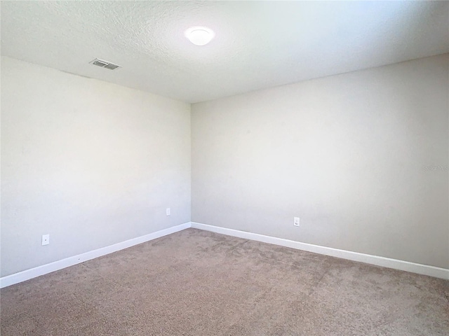 carpeted empty room with a textured ceiling