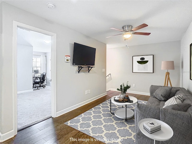 living room with ceiling fan, baseboards, and wood finished floors