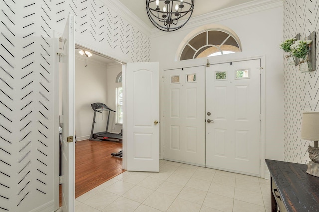 entrance foyer featuring ornamental molding, a notable chandelier, and light hardwood / wood-style floors