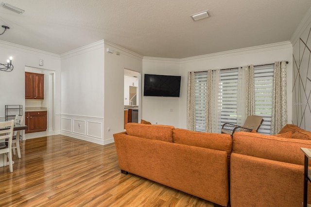 living room with crown molding, a textured ceiling, and light wood-type flooring