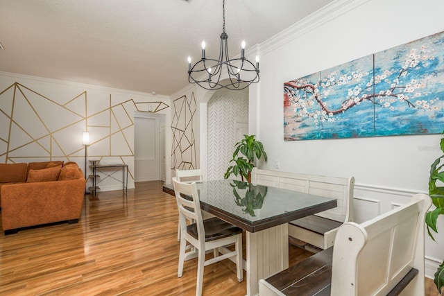 dining space featuring a notable chandelier, ornamental molding, a textured ceiling, and hardwood / wood-style floors