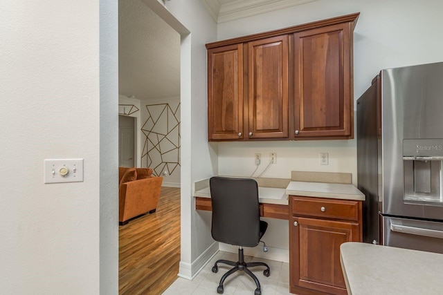 office space featuring light hardwood / wood-style floors, crown molding, and built in desk