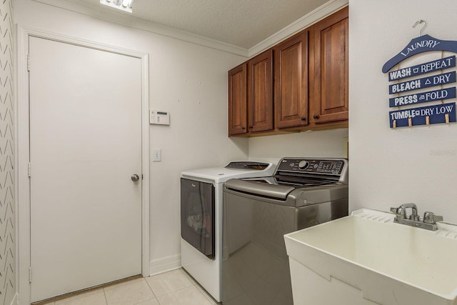 washroom featuring ornamental molding, sink, light tile patterned flooring, separate washer and dryer, and a textured ceiling