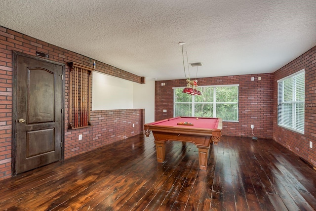 game room featuring brick wall, a textured ceiling, dark hardwood / wood-style floors, and billiards