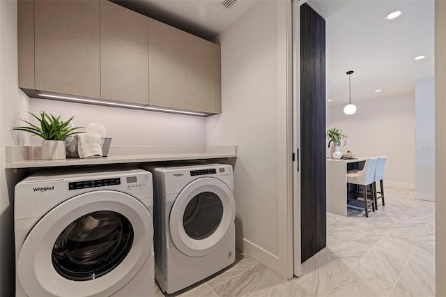 clothes washing area with washer and dryer and cabinets