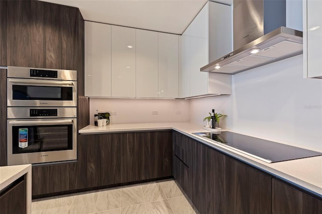 kitchen featuring black electric stovetop, wall chimney exhaust hood, dark brown cabinets, stainless steel double oven, and white cabinets