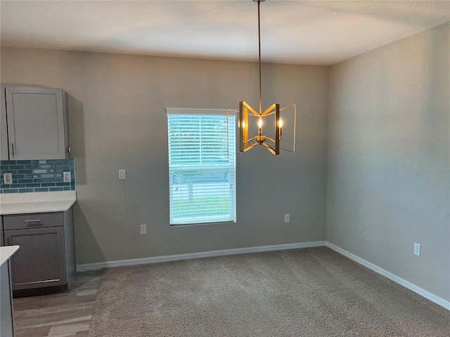 interior space with gray cabinetry, decorative backsplash, carpet floors, an inviting chandelier, and decorative light fixtures