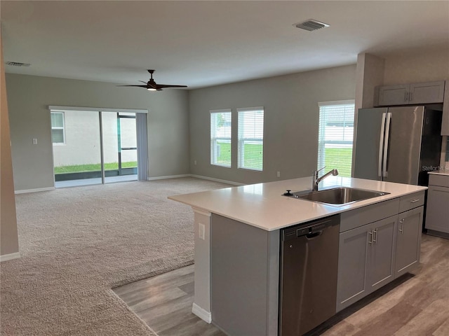 kitchen with ceiling fan, sink, gray cabinetry, a center island with sink, and appliances with stainless steel finishes