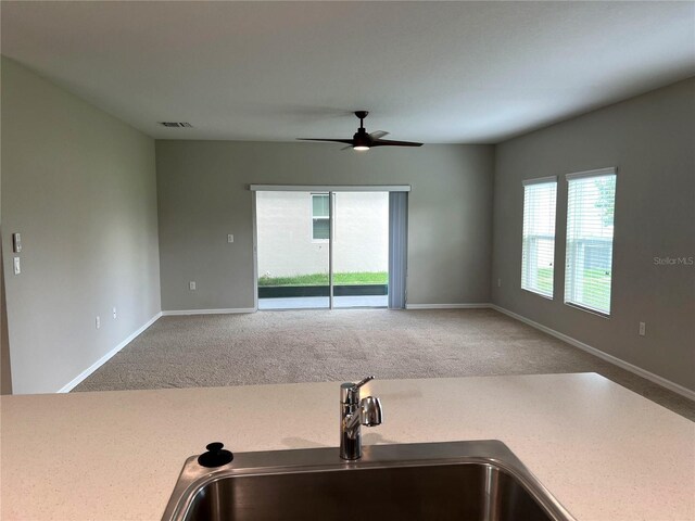 interior space featuring a sink, visible vents, ceiling fan, and carpet