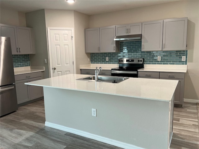 kitchen with an island with sink, sink, gray cabinets, appliances with stainless steel finishes, and light wood-type flooring