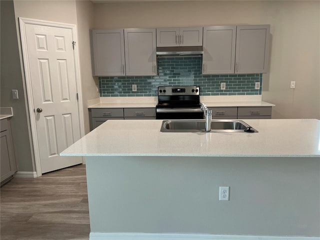 kitchen with gray cabinetry, under cabinet range hood, stainless steel range with electric cooktop, a sink, and wood finished floors