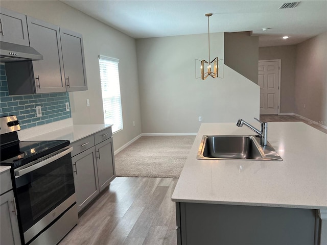 kitchen with stainless steel range with electric stovetop, a sink, gray cabinetry, light wood-style flooring, and decorative backsplash