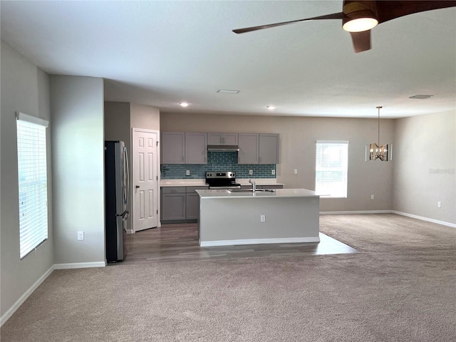 kitchen featuring ceiling fan with notable chandelier, carpet flooring, gray cabinetry, and stainless steel appliances