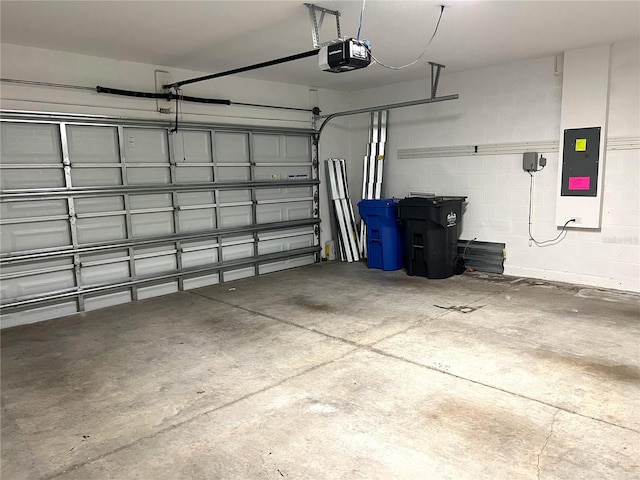 garage with electric panel, a garage door opener, and concrete block wall