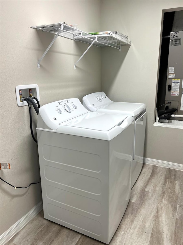 laundry room with washing machine and clothes dryer, light wood-style floors, laundry area, and baseboards