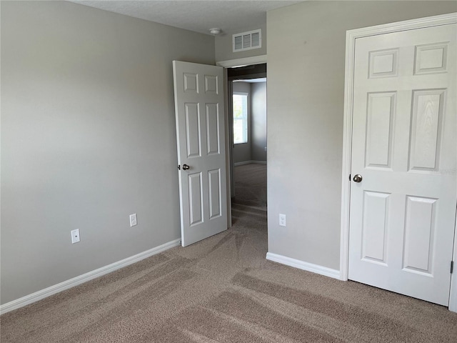 unfurnished bedroom with carpet flooring, visible vents, and baseboards