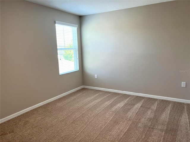 empty room featuring carpet flooring and baseboards