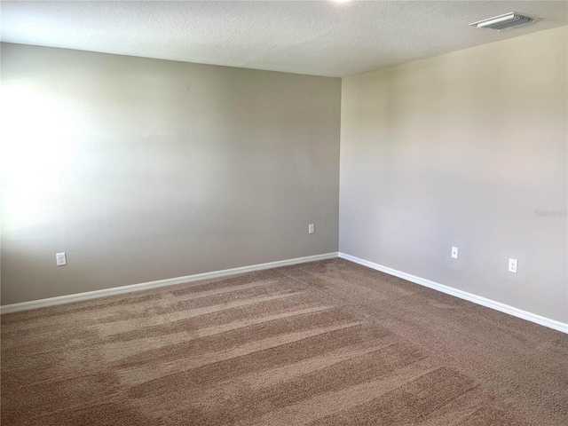 spare room featuring dark colored carpet, baseboards, and a textured ceiling