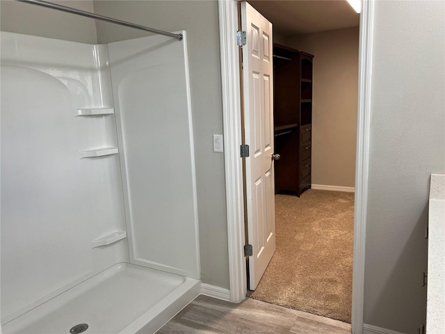 full bathroom with baseboards, a shower stall, and wood finished floors