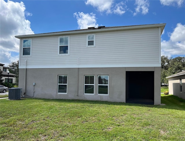 back of house featuring central AC unit, a lawn, and stucco siding