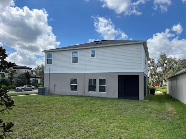rear view of property featuring a yard, central AC unit, and stucco siding