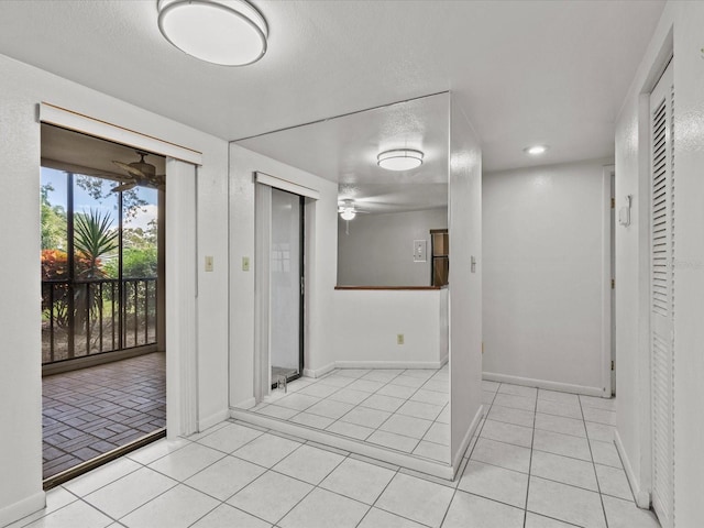 hall with a textured ceiling and light tile patterned floors