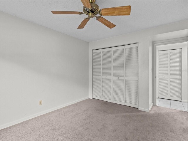 unfurnished bedroom with light carpet, a closet, ceiling fan, and a textured ceiling