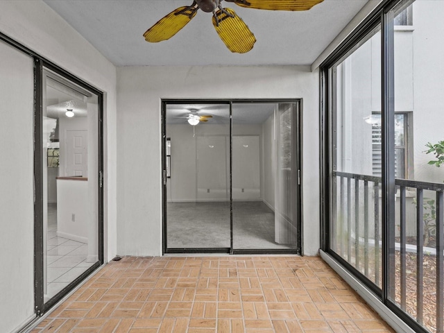 unfurnished sunroom featuring ceiling fan