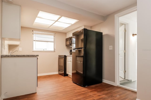 kitchen with black appliances, white cabinetry, and light hardwood / wood-style flooring