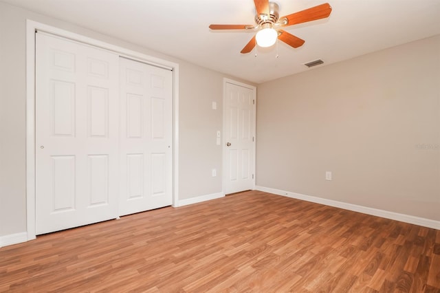 unfurnished bedroom with light wood-type flooring, ceiling fan, and a closet