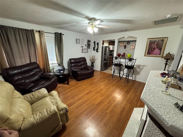 living room featuring ceiling fan, hardwood / wood-style flooring, and a textured ceiling