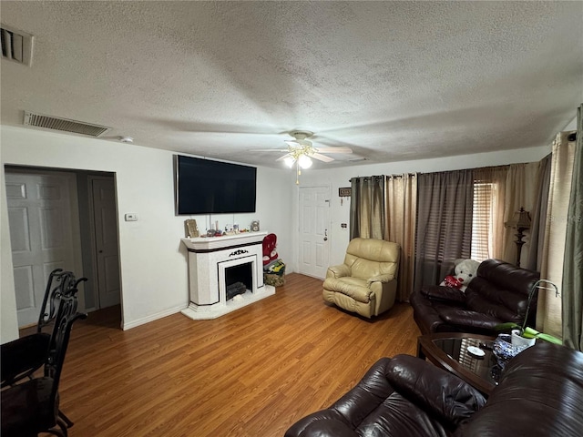 living room featuring ceiling fan, a textured ceiling, and hardwood / wood-style floors