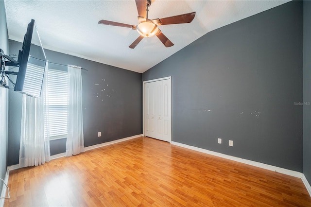 spare room with ceiling fan, a textured ceiling, hardwood / wood-style floors, and vaulted ceiling