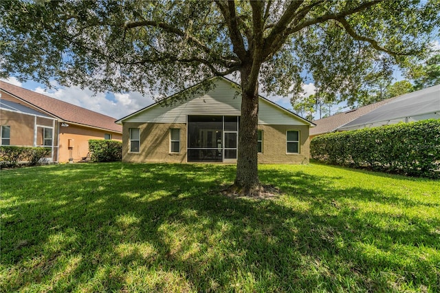 rear view of house featuring a lawn and a sunroom