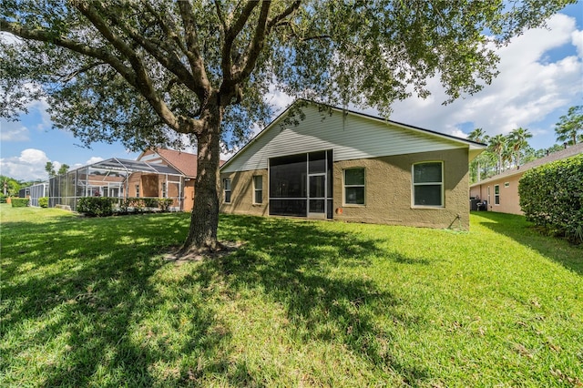 back of property with glass enclosure, a lawn, and a sunroom