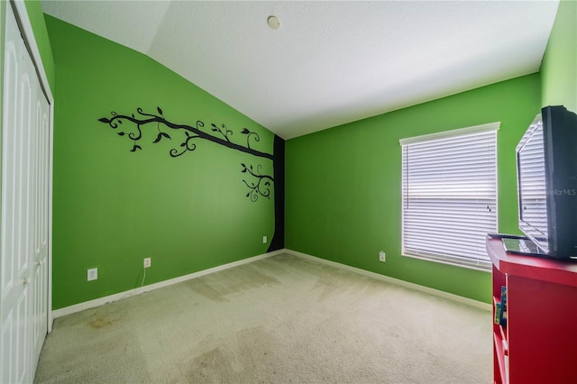 unfurnished bedroom with vaulted ceiling, light colored carpet, and a closet