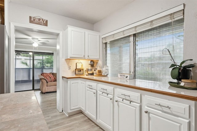 kitchen with ceiling fan, white cabinets, light wood-type flooring, and tasteful backsplash