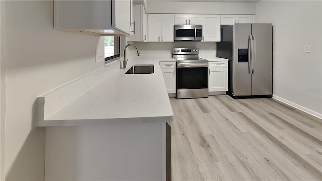 kitchen with stainless steel appliances, white cabinetry, light hardwood / wood-style floors, and sink