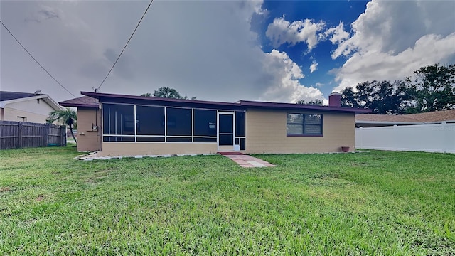 back of property with a lawn and a sunroom