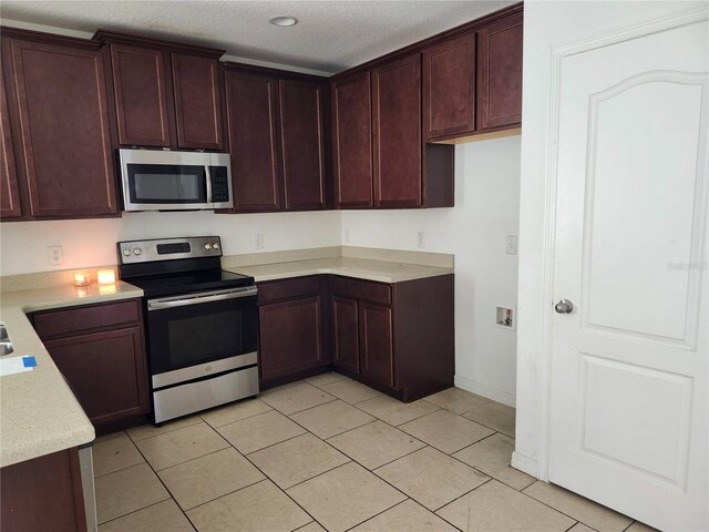 kitchen with appliances with stainless steel finishes, a textured ceiling, and light tile patterned floors