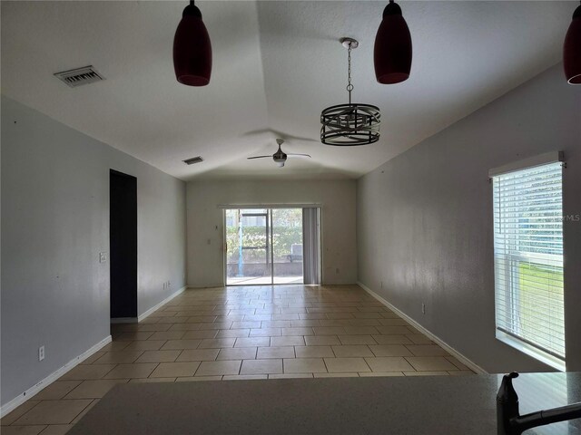 tiled spare room with ceiling fan with notable chandelier and vaulted ceiling