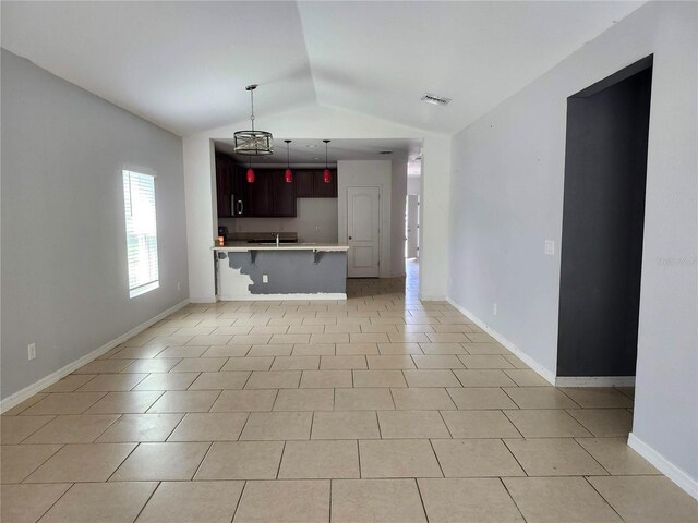 kitchen featuring lofted ceiling, kitchen peninsula, a kitchen bar, and light tile patterned floors