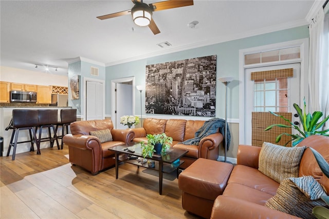 living room with crown molding, ceiling fan, and light hardwood / wood-style flooring