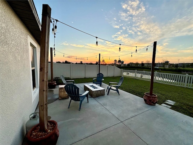 patio terrace at dusk featuring a yard and an outdoor fire pit