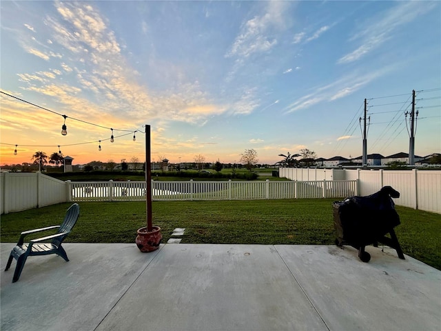 patio terrace at dusk featuring a lawn