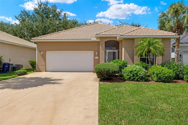 mediterranean / spanish house with central air condition unit, a garage, and a front lawn