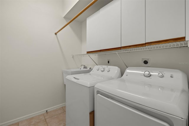 washroom featuring washing machine and dryer, sink, light tile patterned flooring, and cabinets